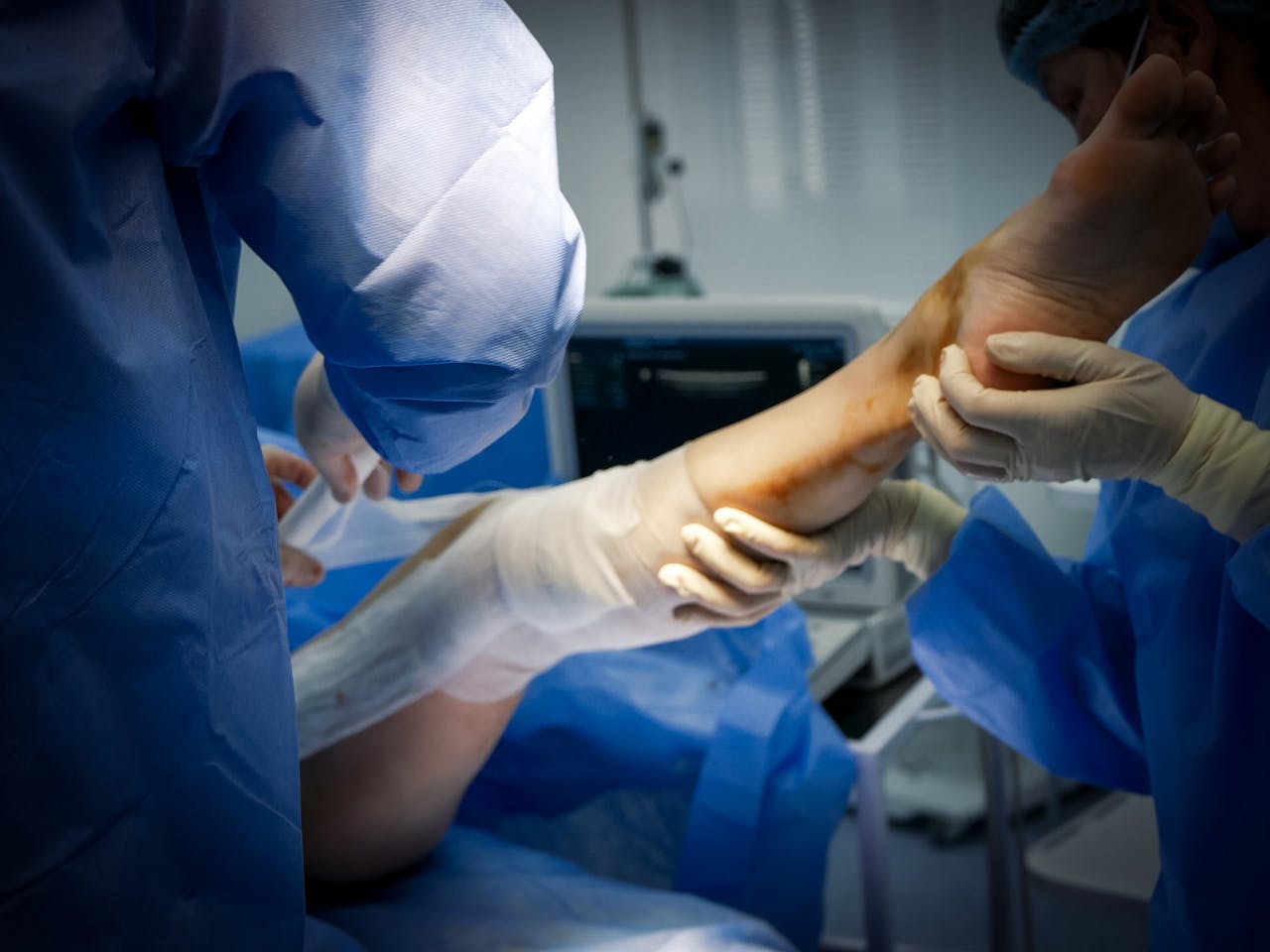 Close-up of doctors treating a patient's leg in a surgical room setting.